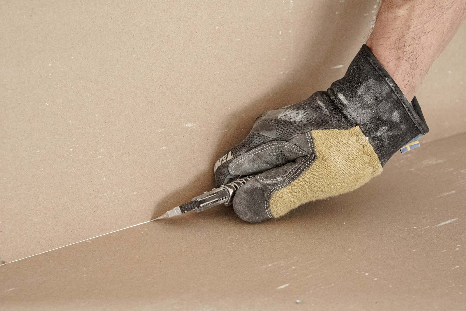 Mano con guante de trabajo repasando una pared con la espátula