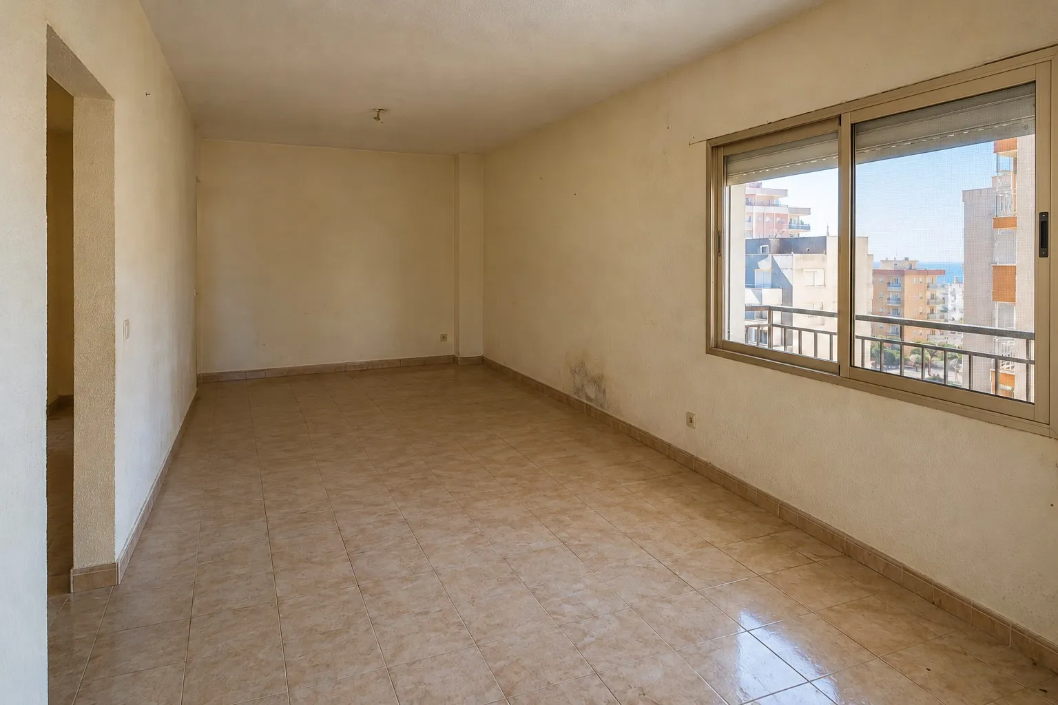 Salón de piso en Los Boliches, Fuengirola, con manchas de humedad en la pared antes de la reforma